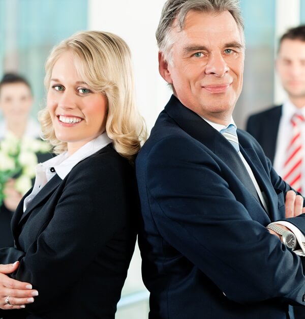 Male and female senior leadership team members standing back to back. Get qualified for a strategic leadership role with Skills Recognition.